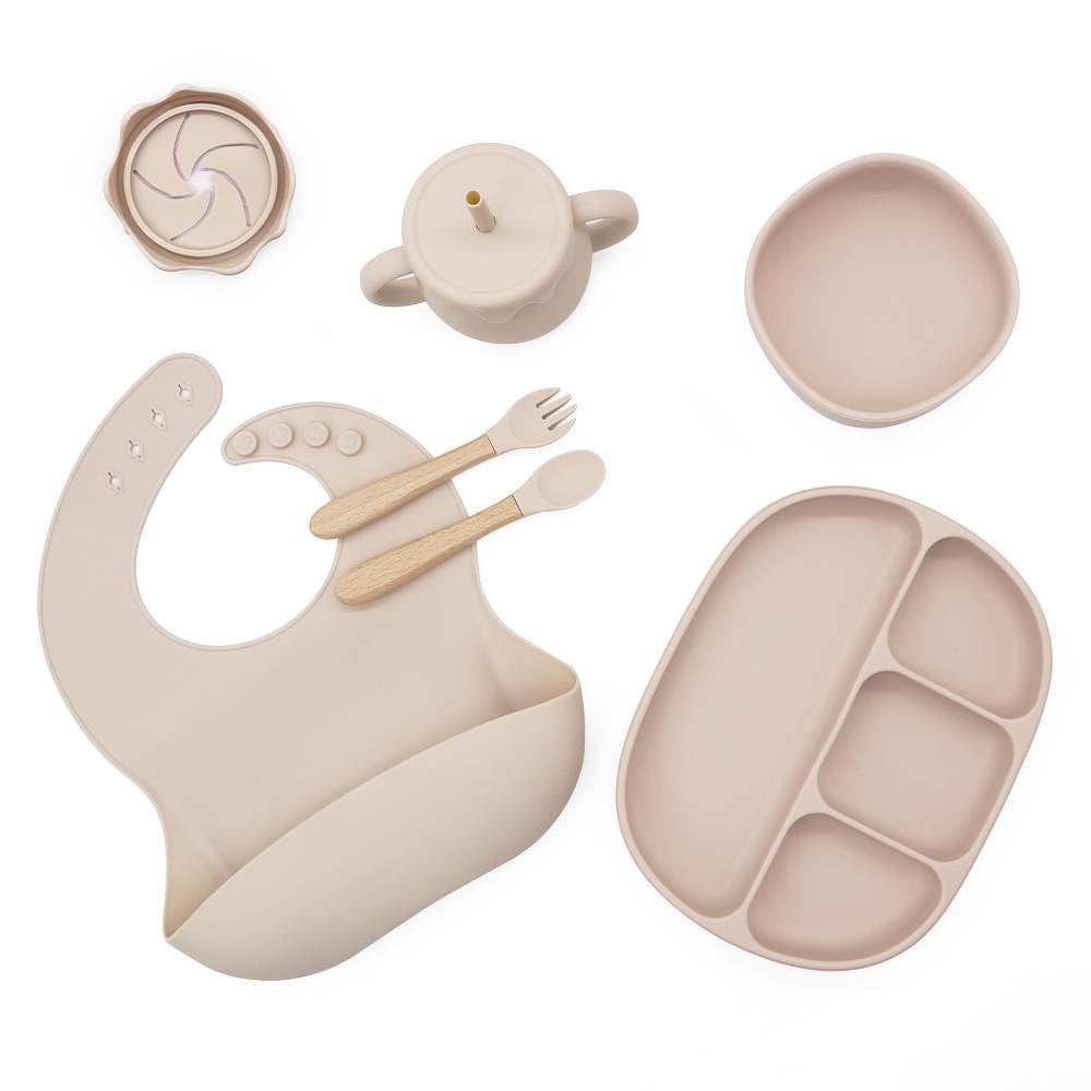 Children's dining set with bib, plate, bowls, and utensils on a white background